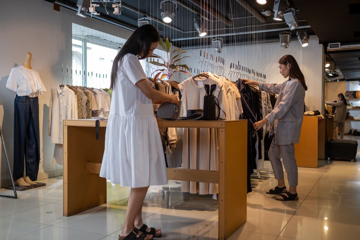Two customers browsing clothes in a bright shop