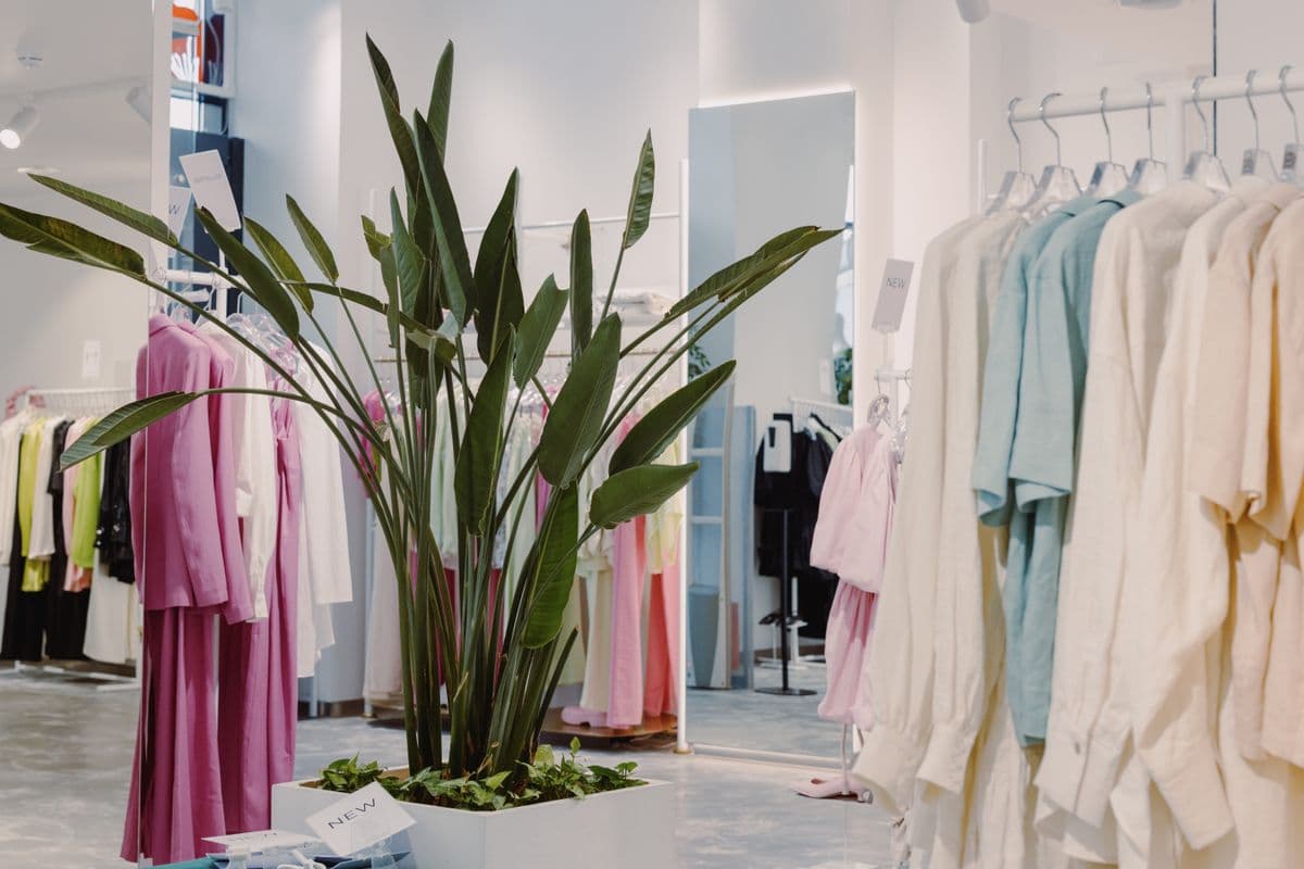 Bright shop interior with pastel garments on rails